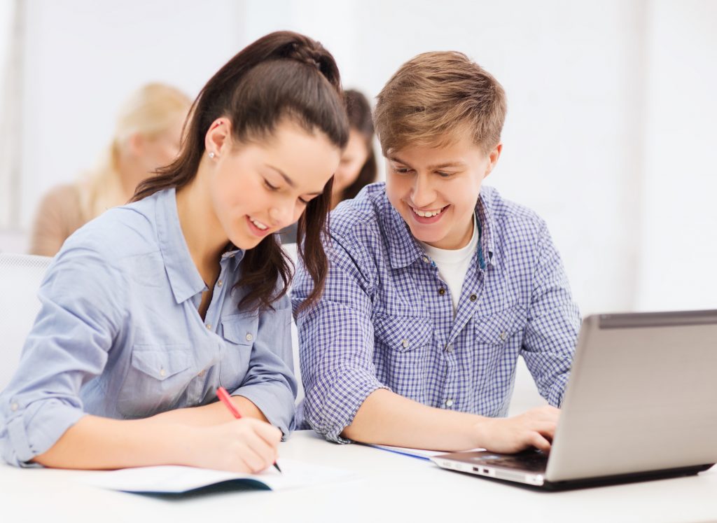 education, technology, people and internet concept - two smiling students with laptop and notebooks at school